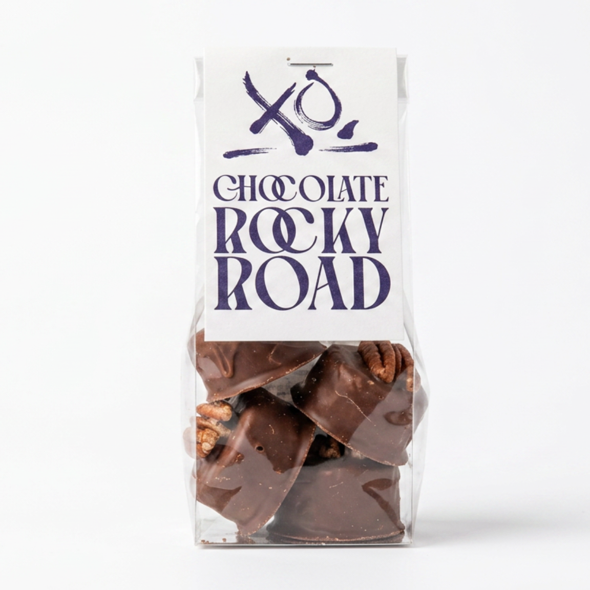 A clear plastic bag of Rocky Road chocolate bark with a white label featuring the brand name 'XO CHOCOLATE ROCKY ROAD' and a XO chocolate logo, set against a plain white background.